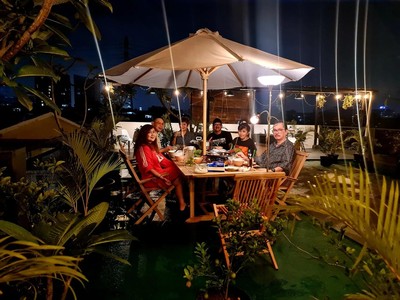Cozy place on a roof top over Jakarta where people enjoy together while sitting on a stylisch set of wooden teak chairs and table.