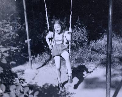 Child swings on a hanging swing in an outdoor area.