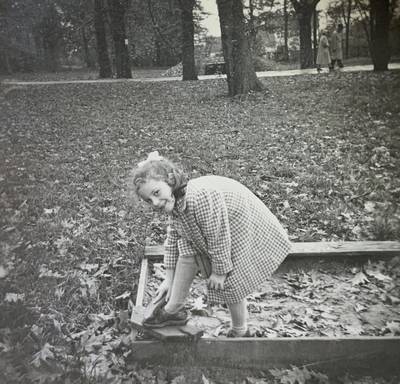 A girl is playing in a sandbox surrounded by simple, rough boards on which one rammed many splinters under one's skin ;)