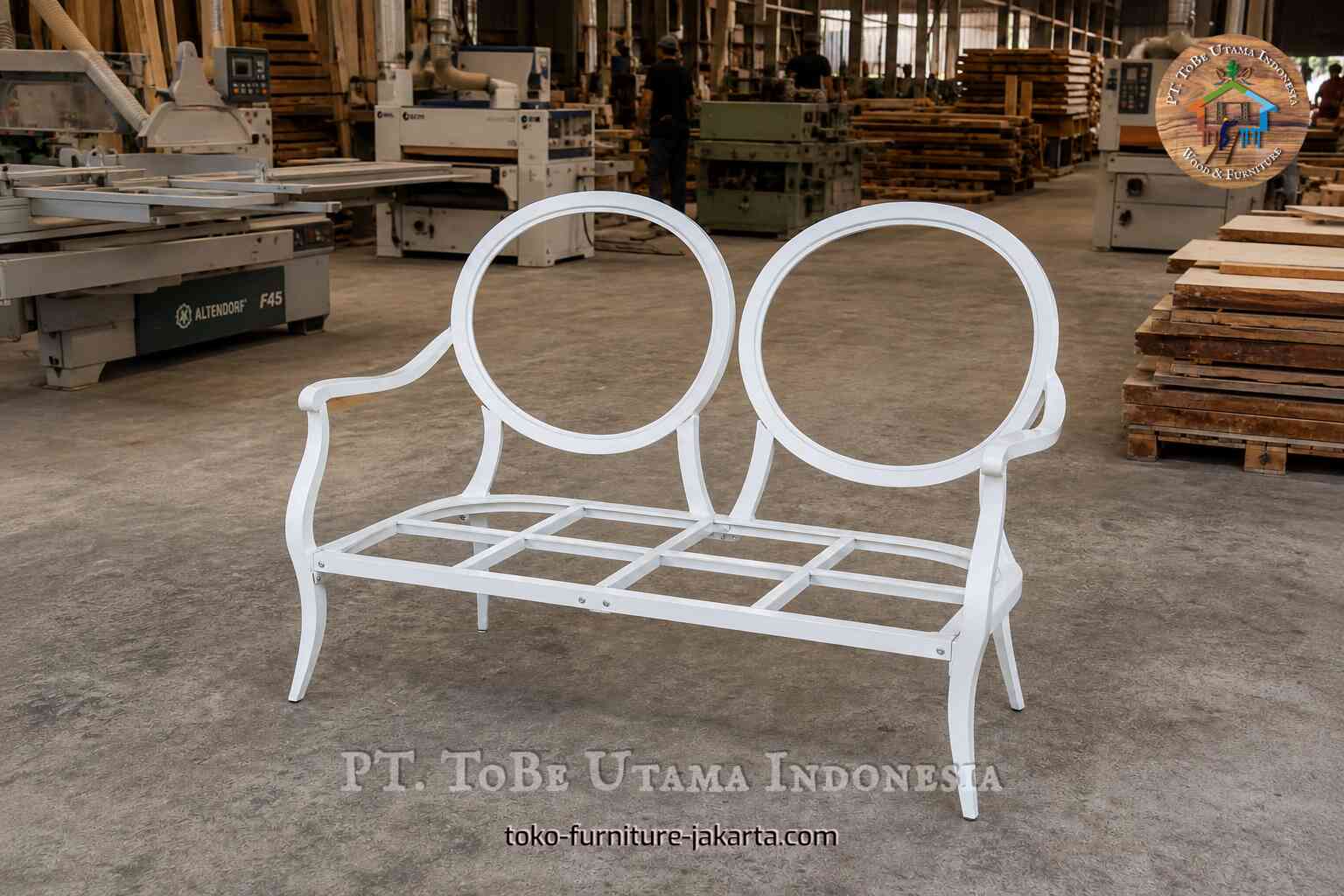 Rangka furnitur dua tempat duduk berwarna putih dengan sandaran melengkung di sebuah bengkel.