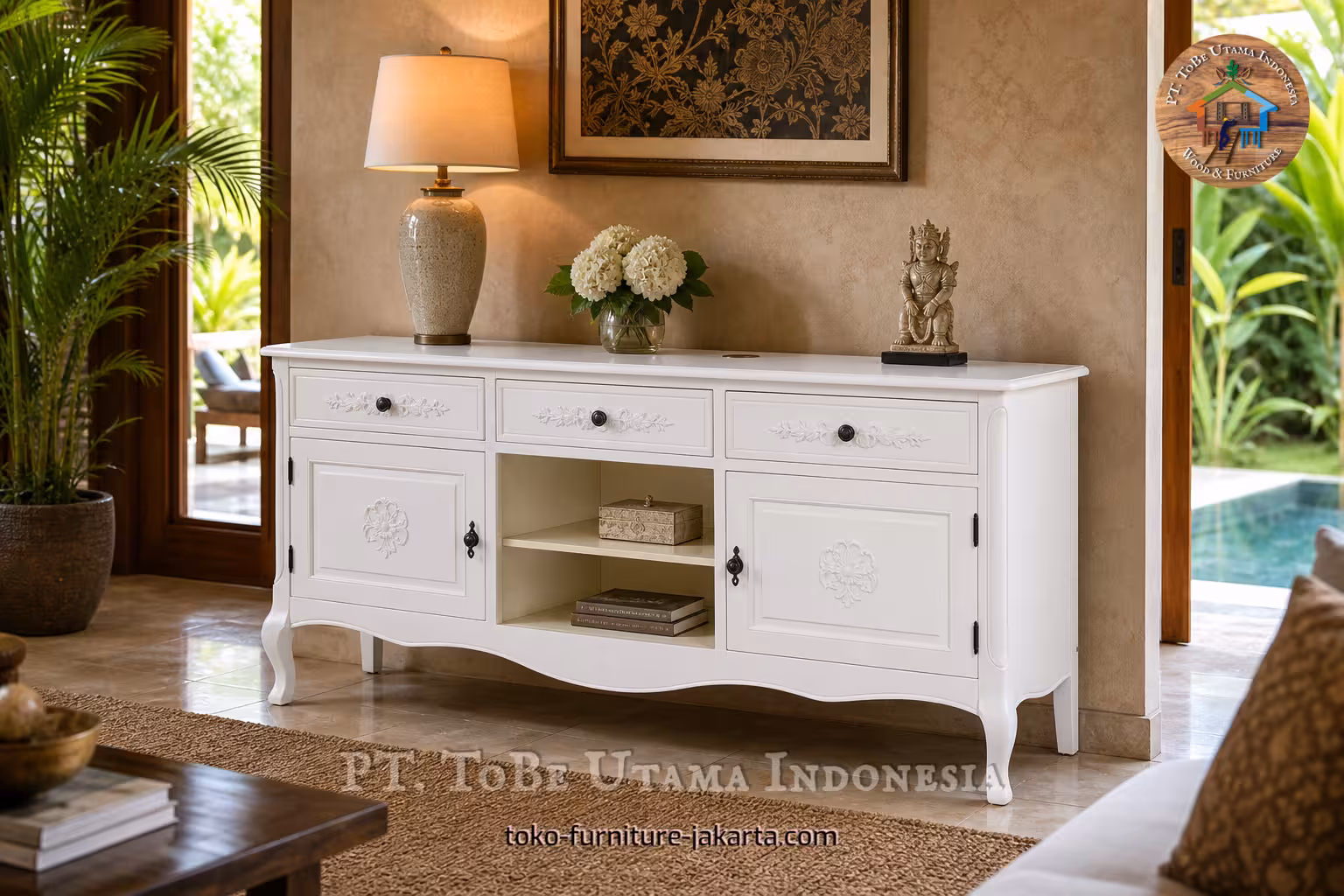 White cupboard with three drawers styled in a tropical living room with lamp, flowers, and garden view