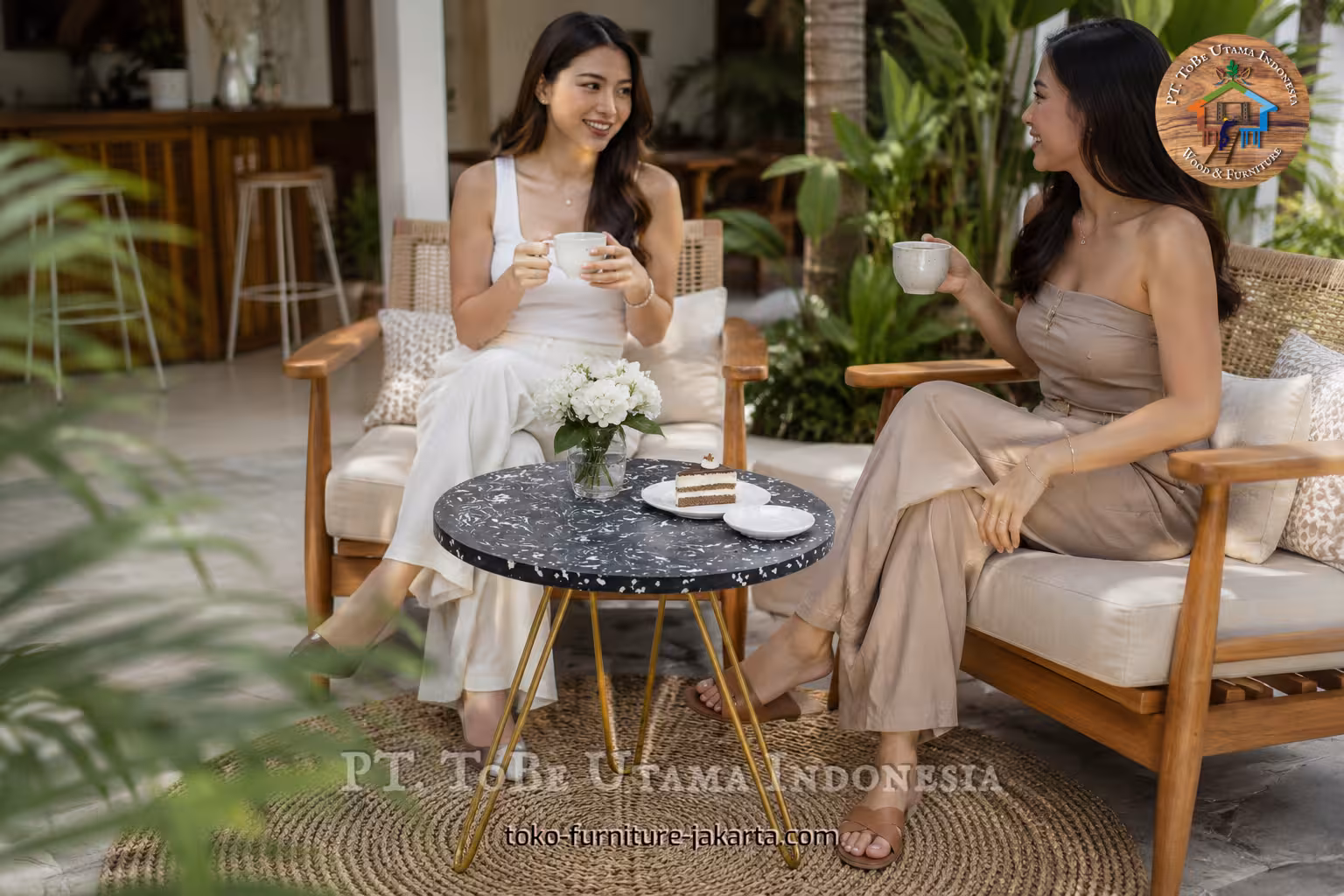 Round black speckled coffee table with gold legs on a tropical patio between two women drinking coffee
