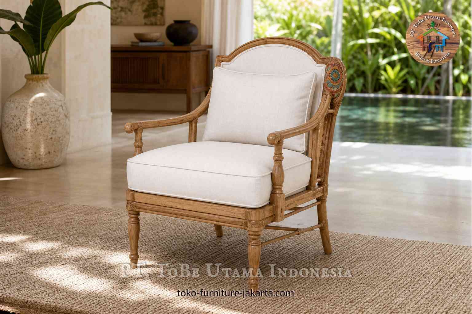 Kursi berlengan kayu bergaya vintage dengan bantalan krem, sandaran tangan melengkung, kaki berukir, dan detail samping bermotif.